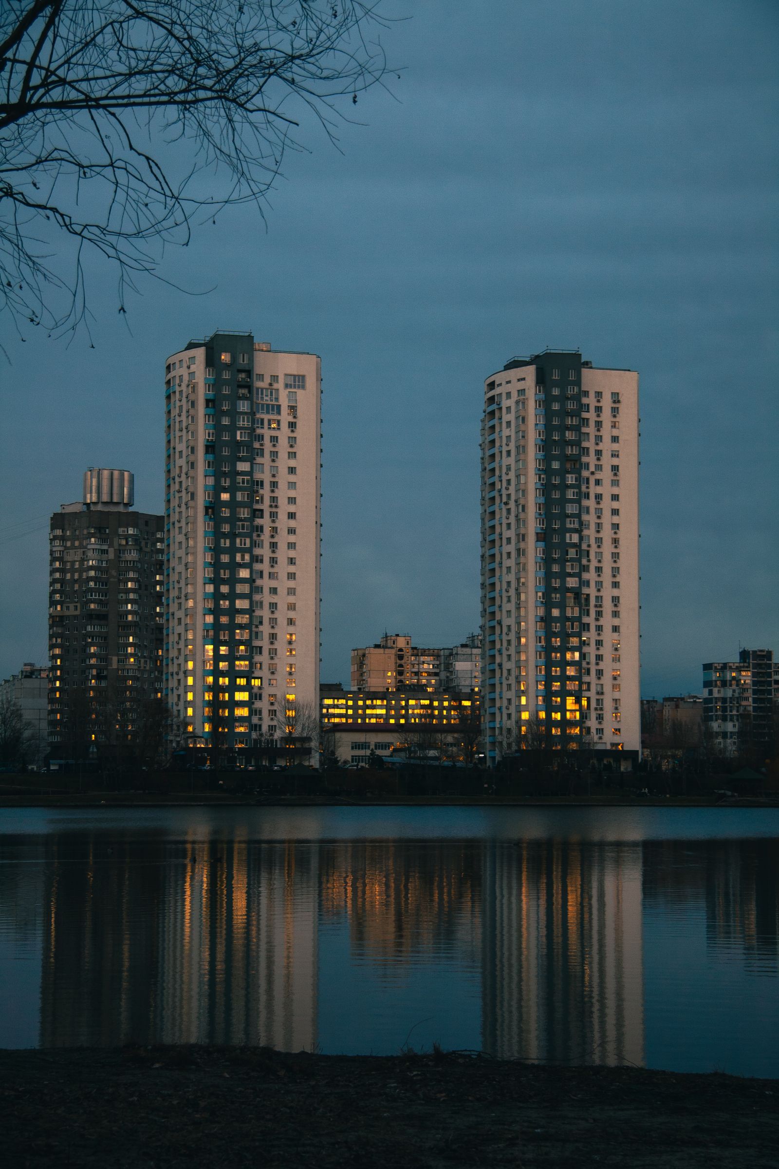 Tall buildings reflected in still water at dusk