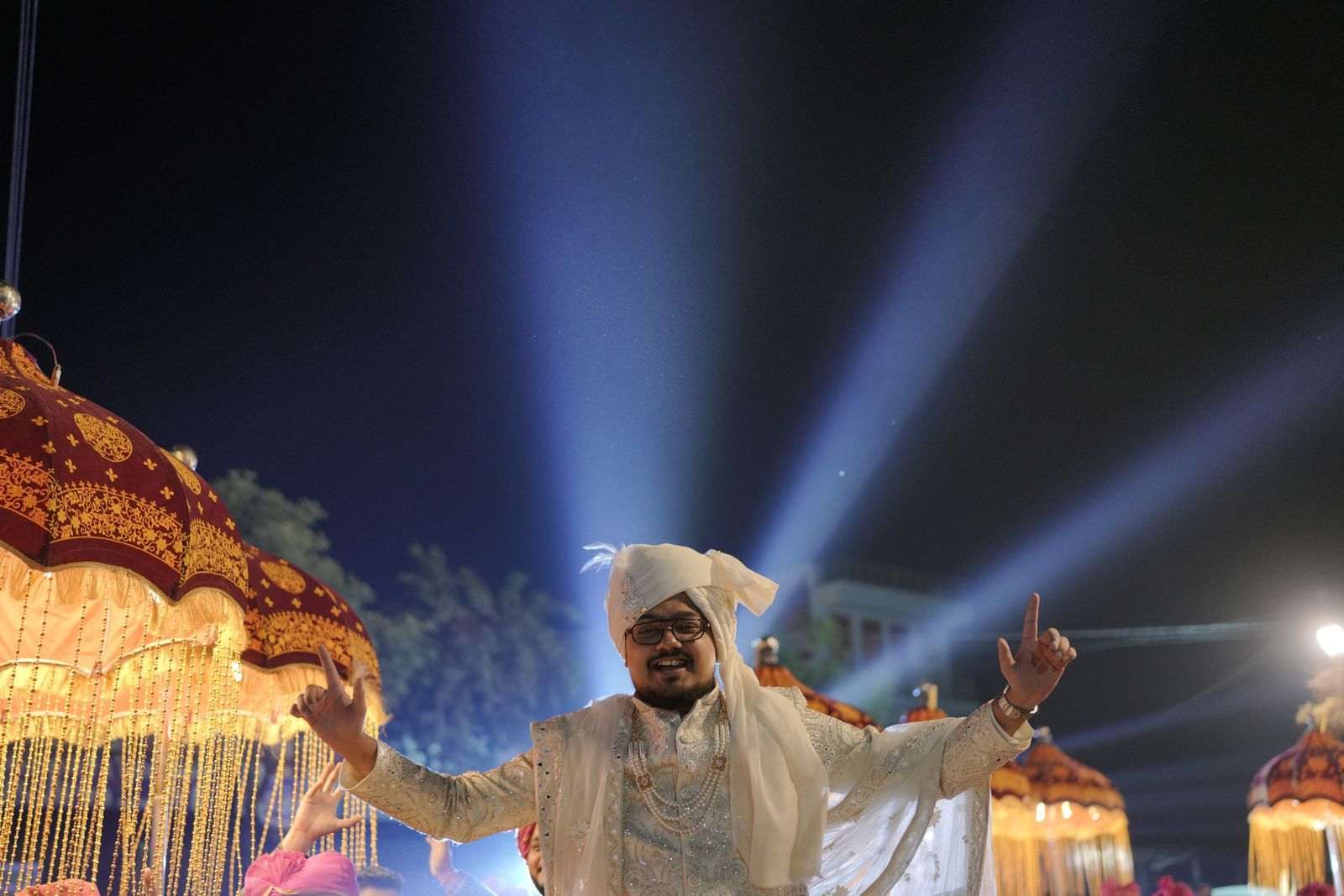 A groom celebrating under beams of light
