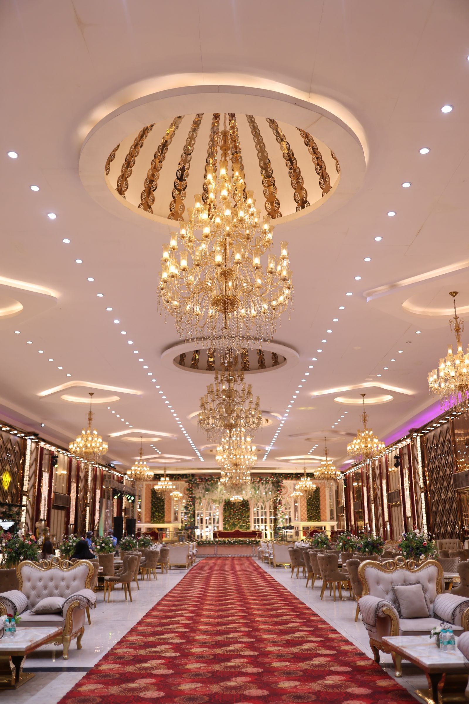 A grand hall with chandeliers set for a wedding