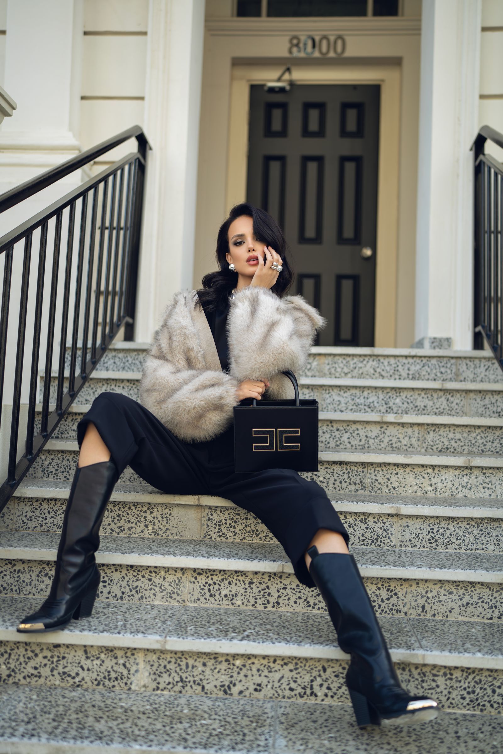 A woman in a fur coat with a handbag on marble steps