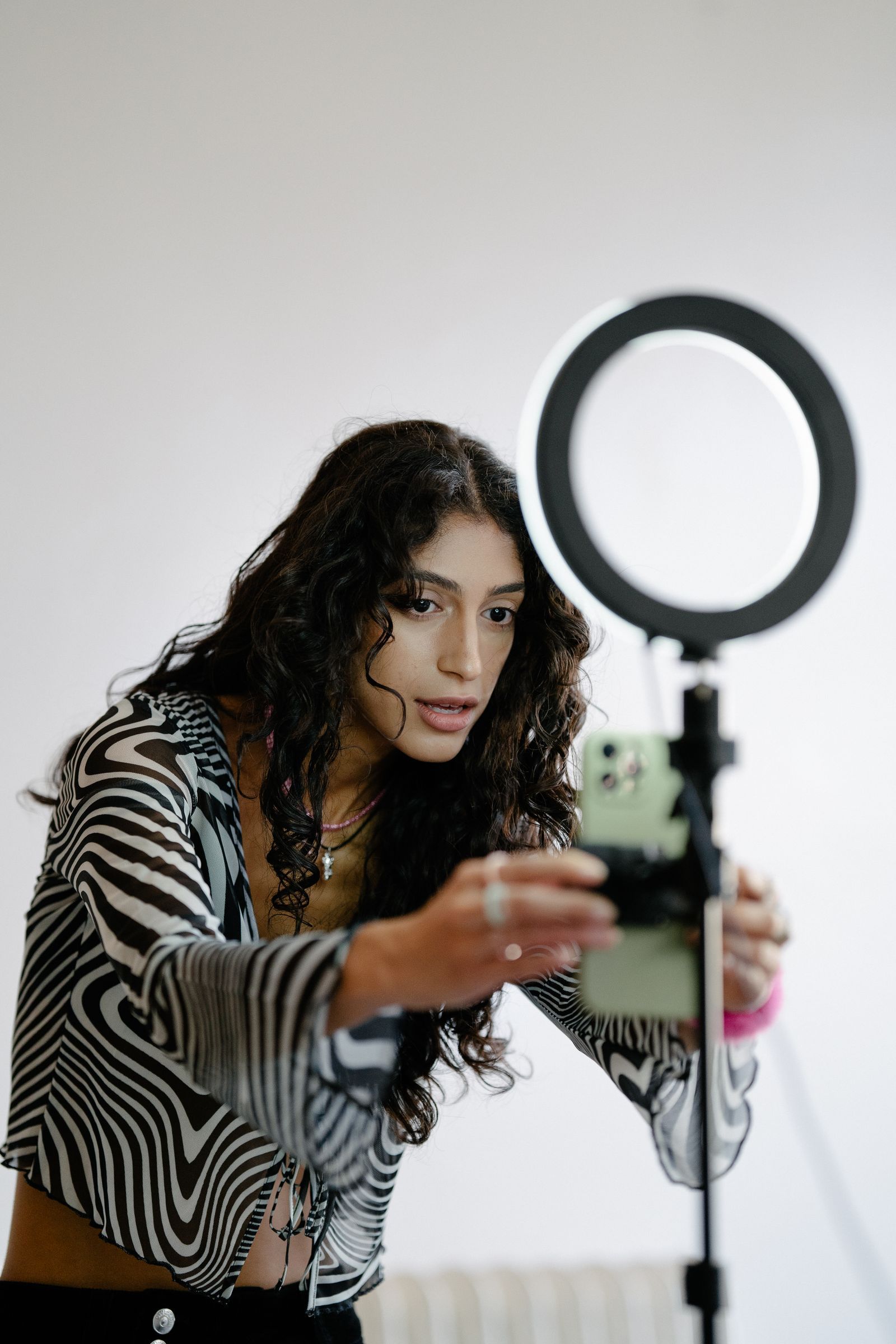 A creator filming herself on a phone in front of a ring light